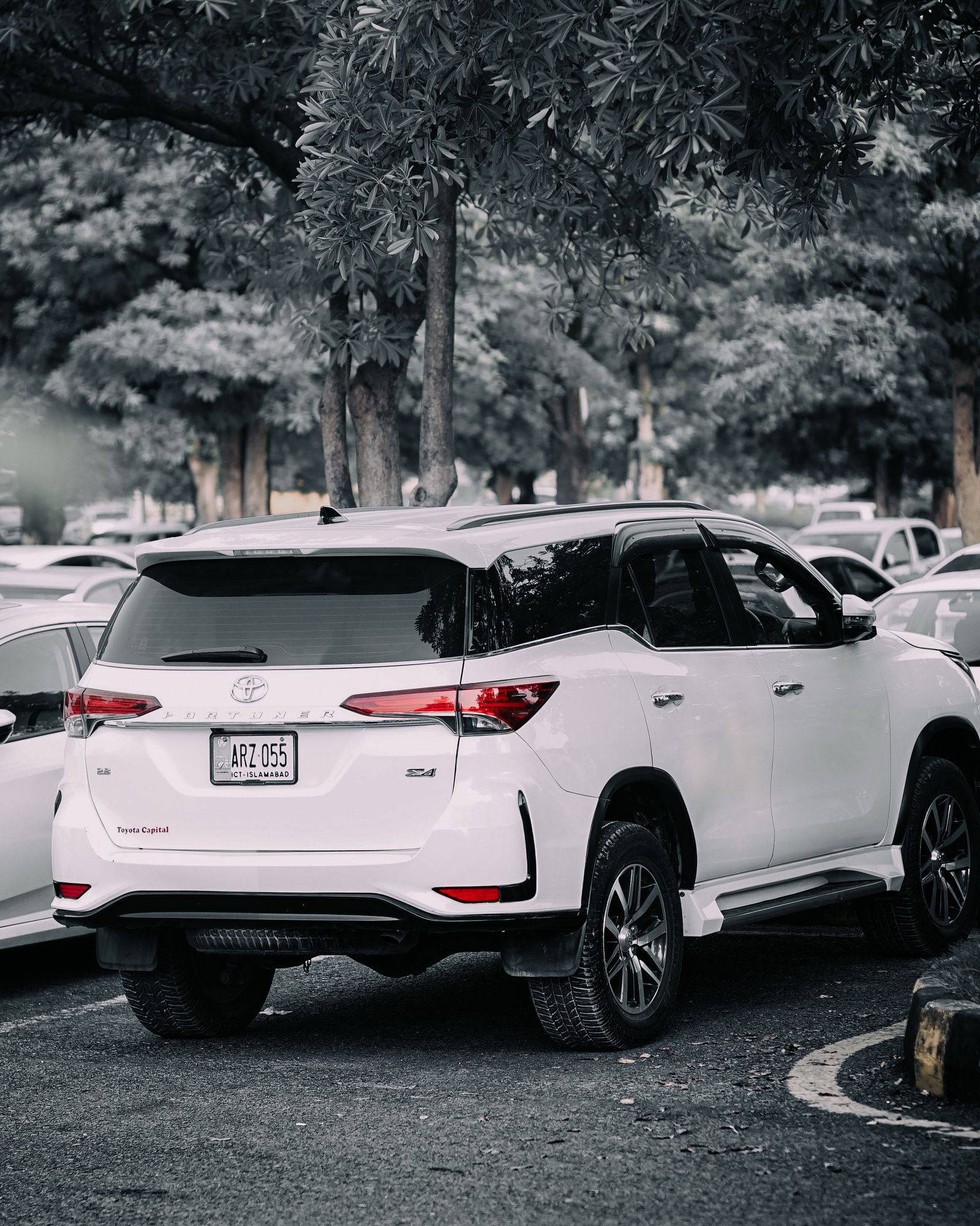 White Toyota Fortuner SUV parked under trees