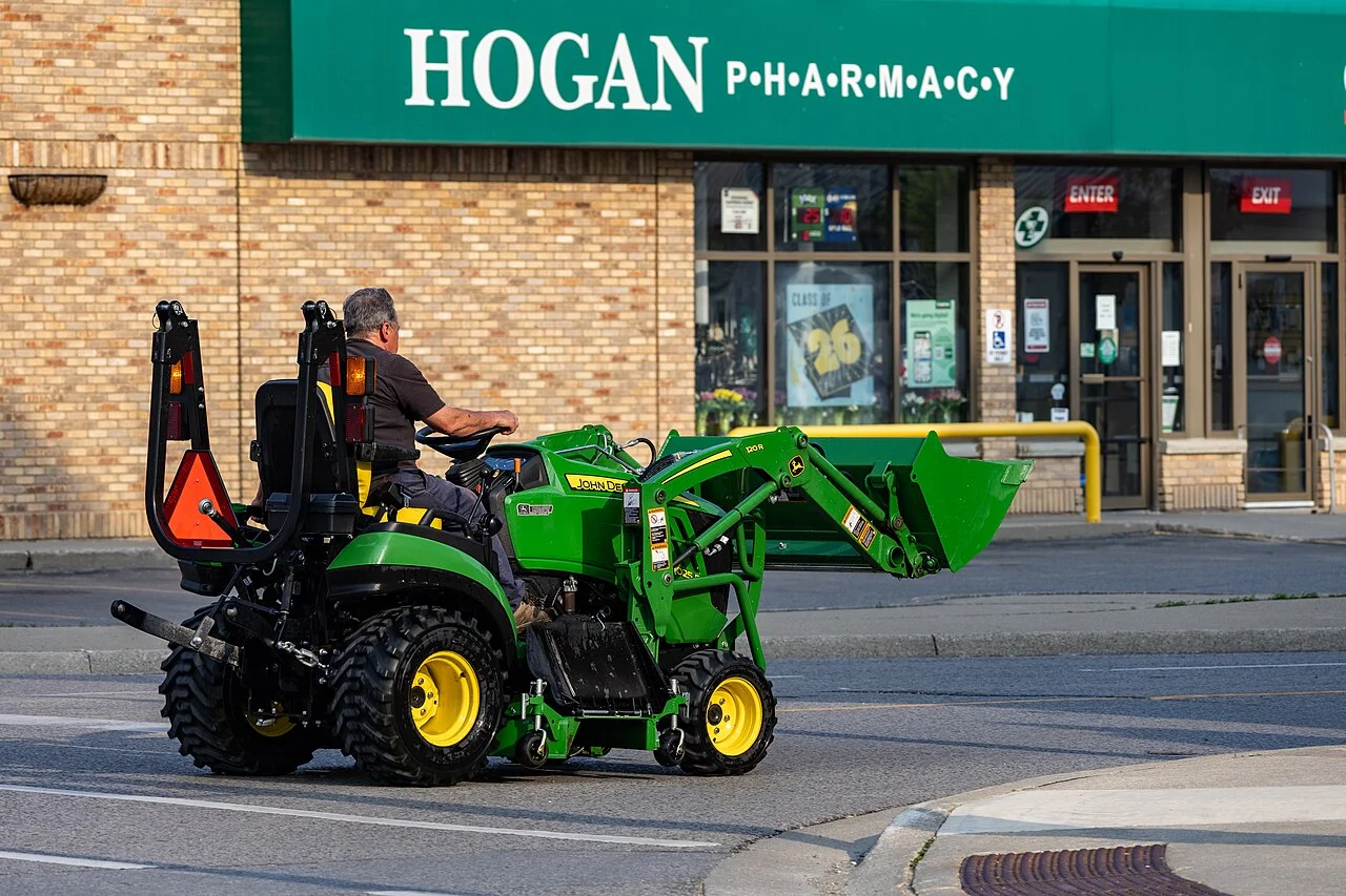 Man driving John Deere 1025R on street, Petrolia, Ontario, 2026-05-17
