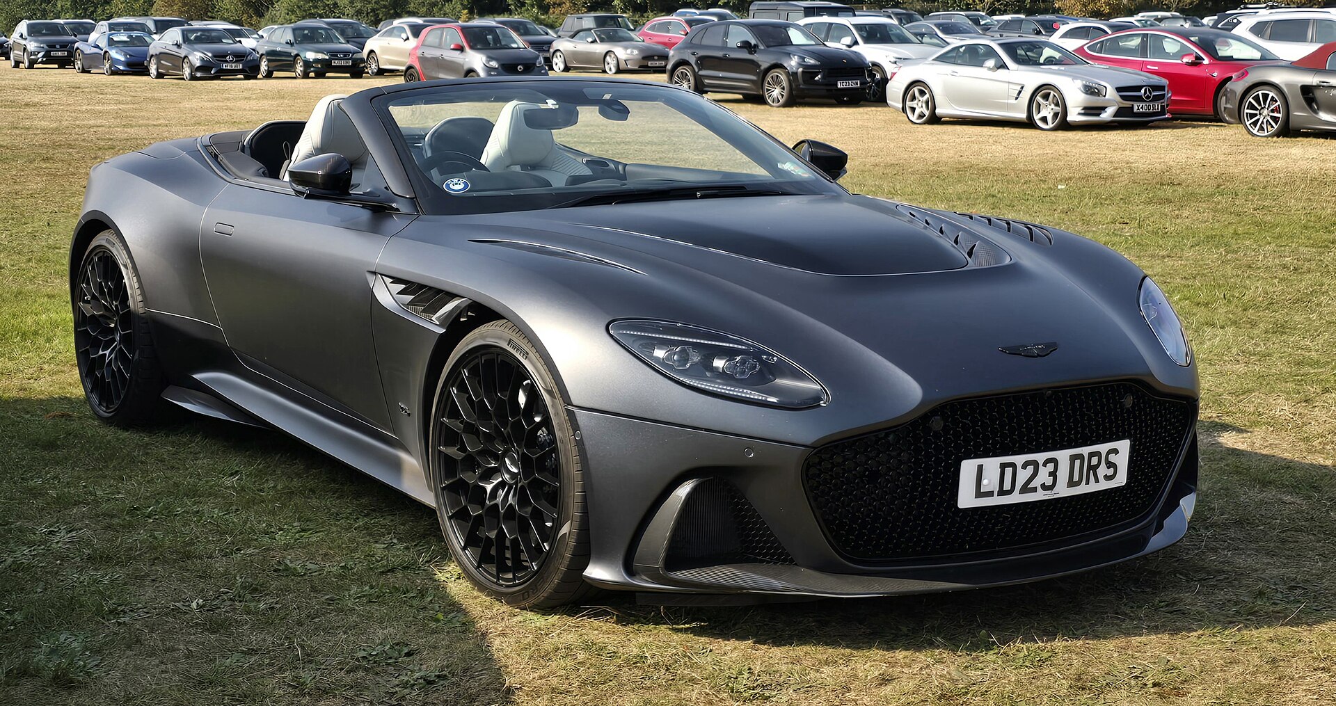 Matte grey Aston Martin DBS 770 Ultimate Volante convertible parked on grass