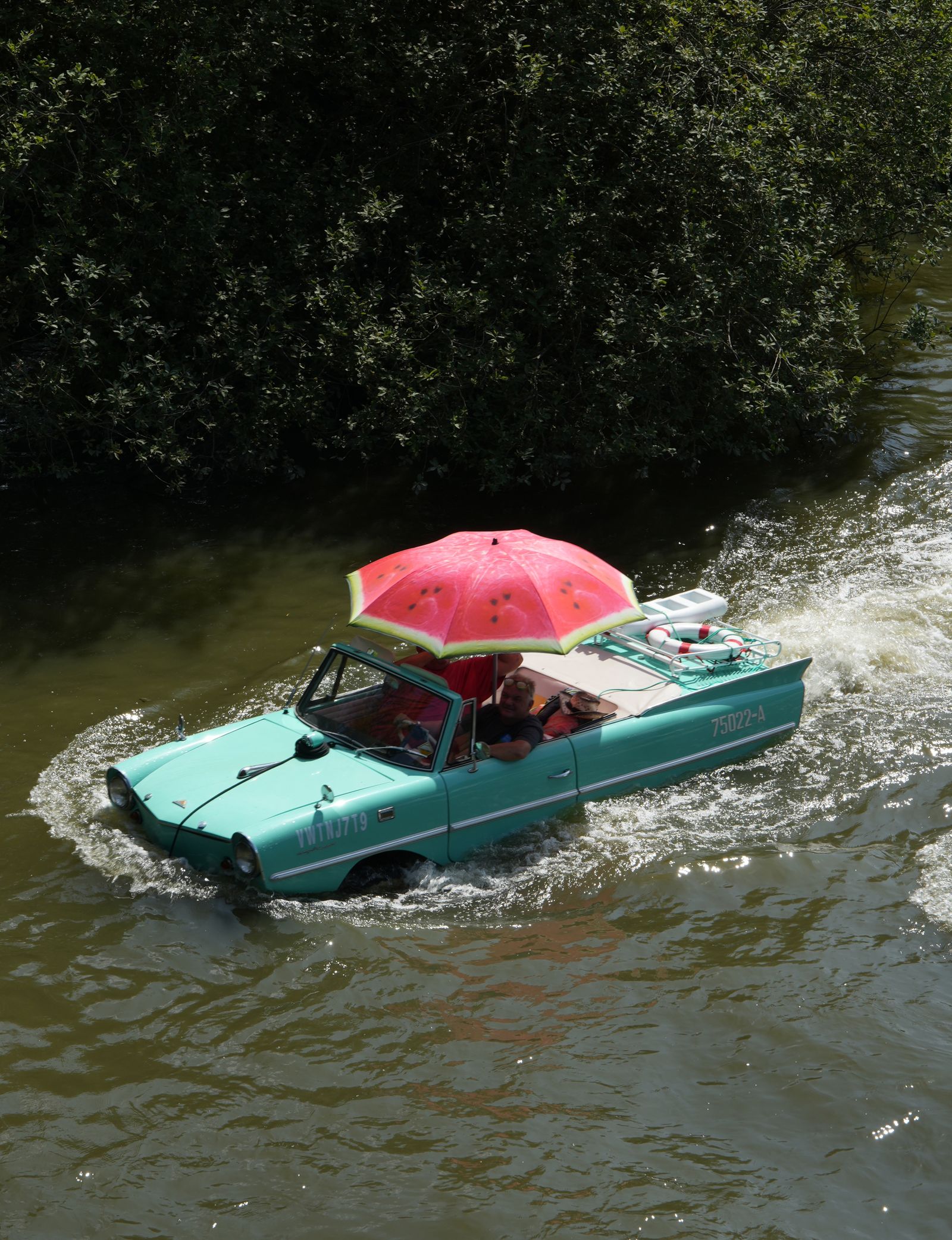 Amphicar turquesa navegando por un río