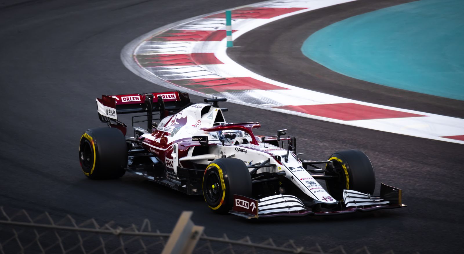 Monoplaza Alfa Romeo de Fórmula 1 rojo y blanco con el número 7 en un circuito