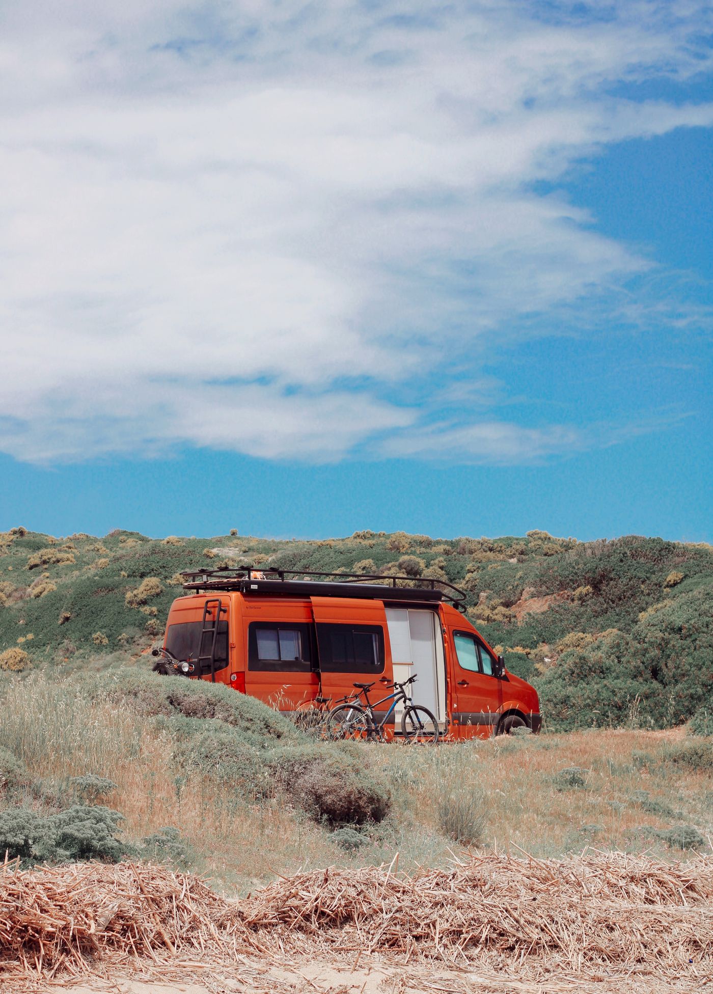 Orange camper van with camping equipment parked on grass