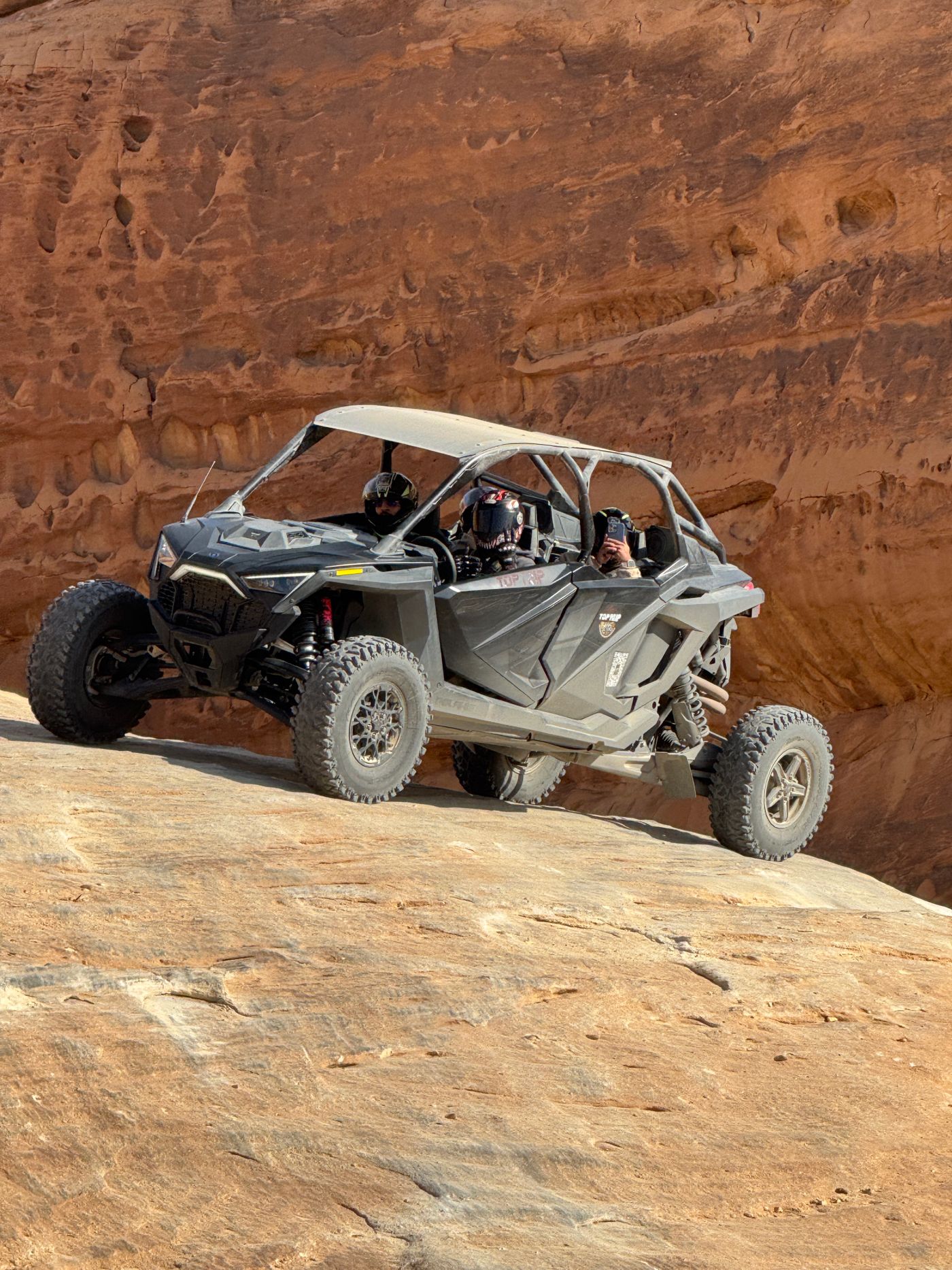 Four-seat Polaris RZR climbing a rocky trail