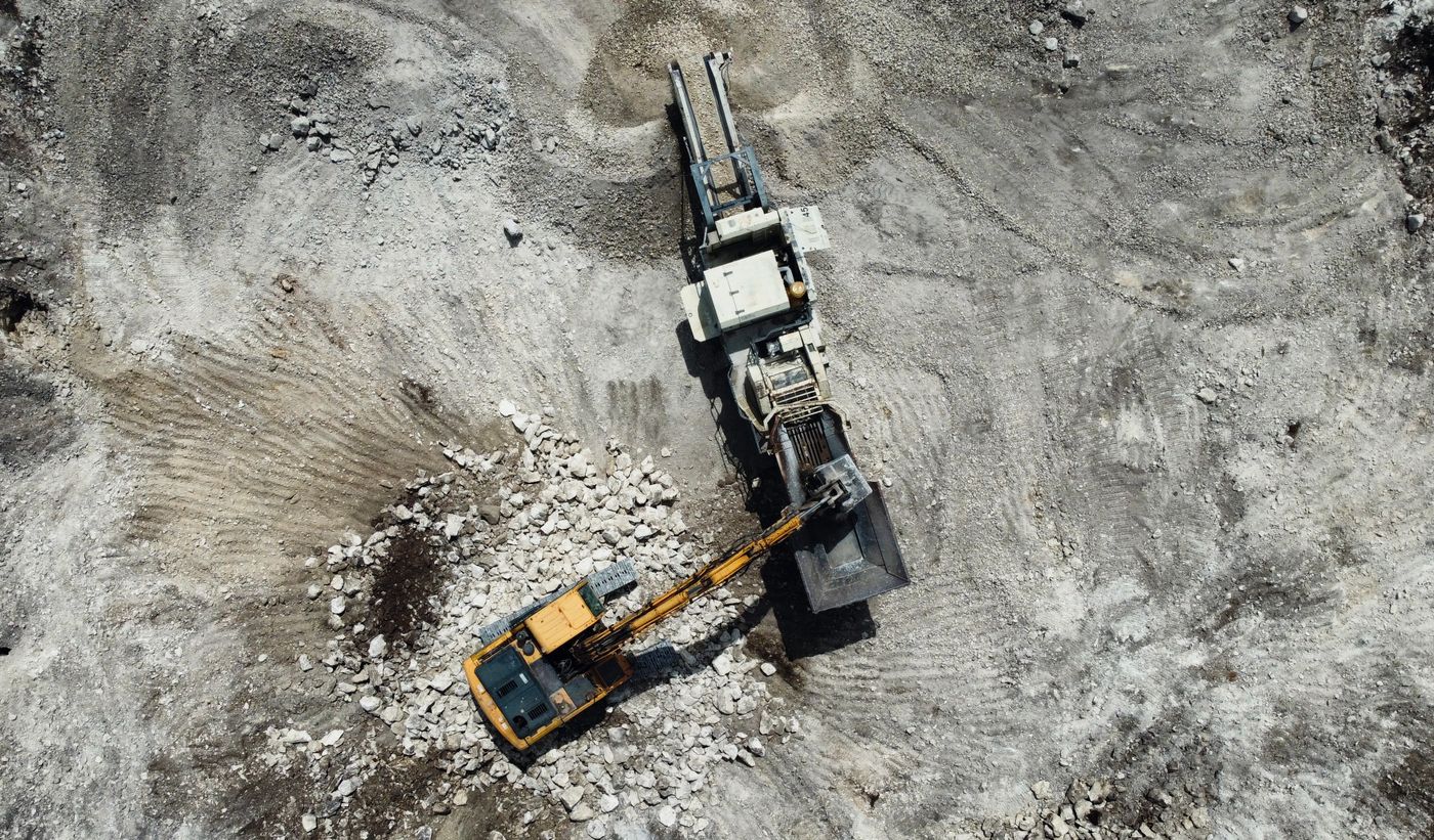 Excavadora hidráulica cargando material junto a una tolva de cantera