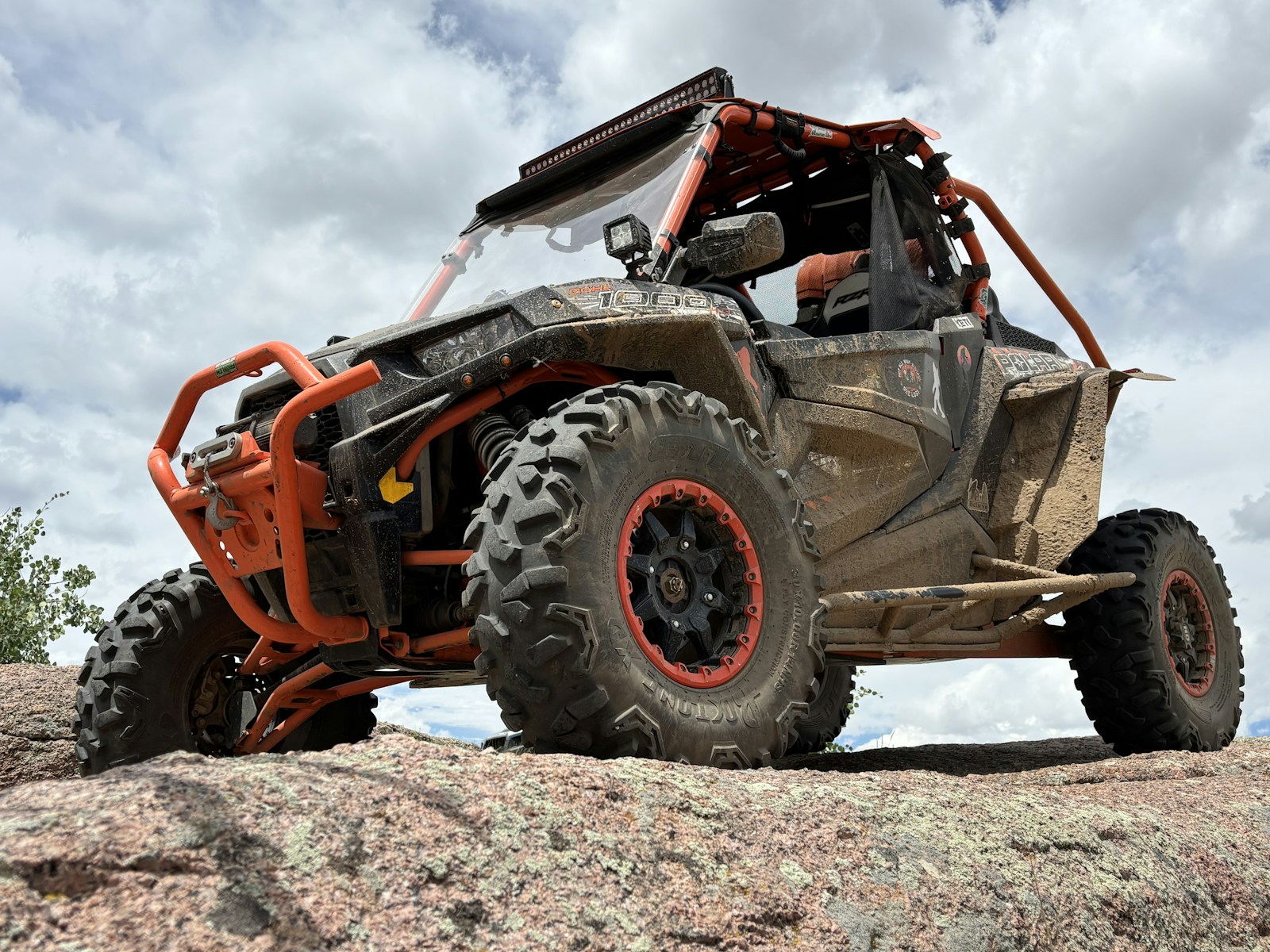 Side-by-side vehicle with an orange roll cage on rocky terrain