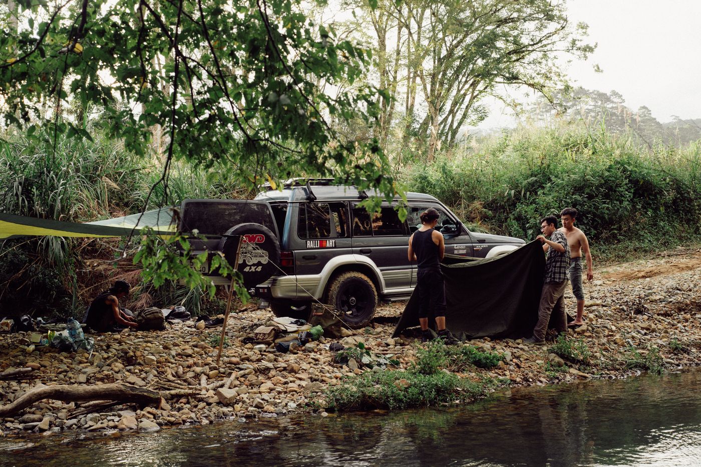 Mitsubishi Pajero and campers beside a wooded stream