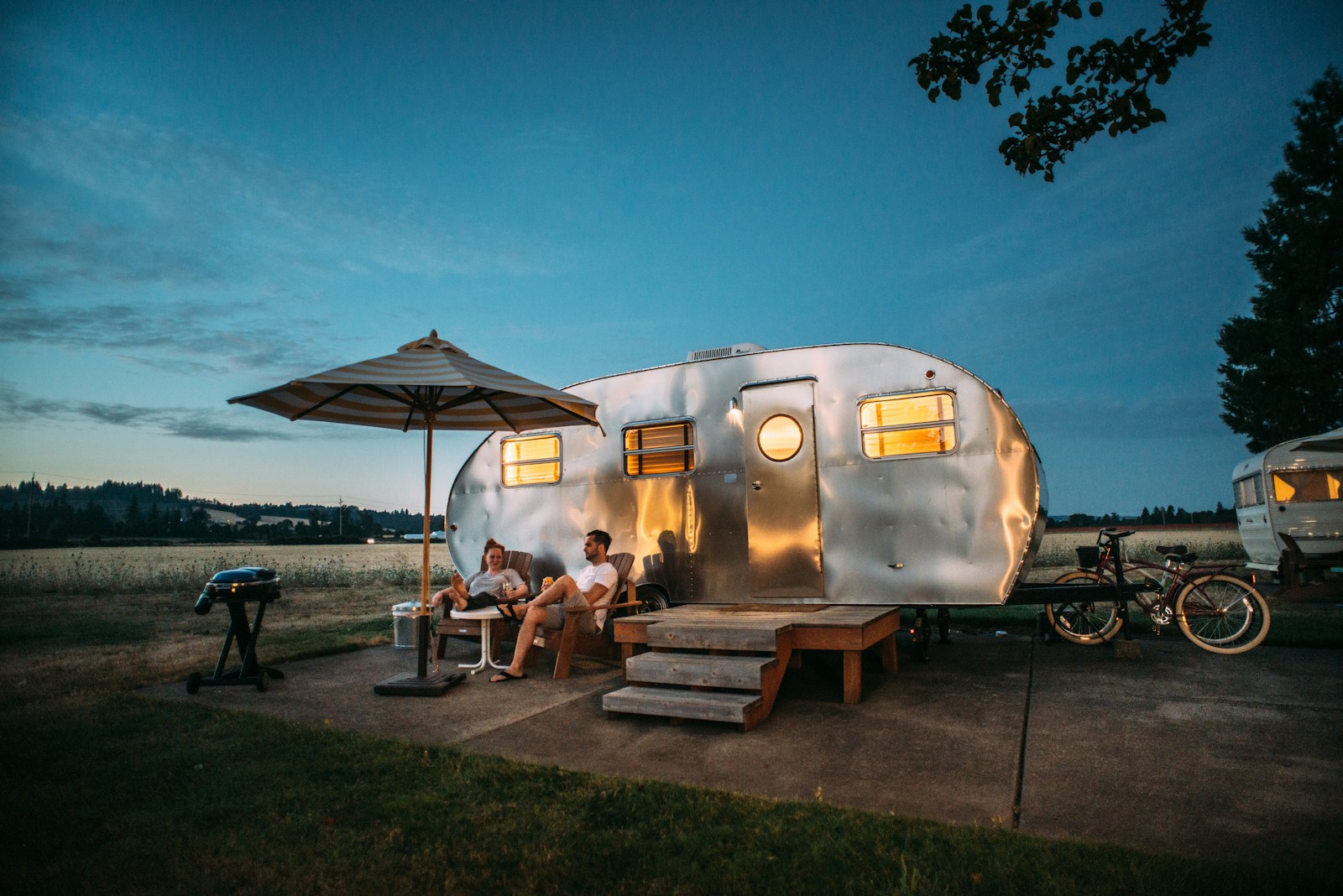 Aluminium travel trailer at a rural campsite at dusk