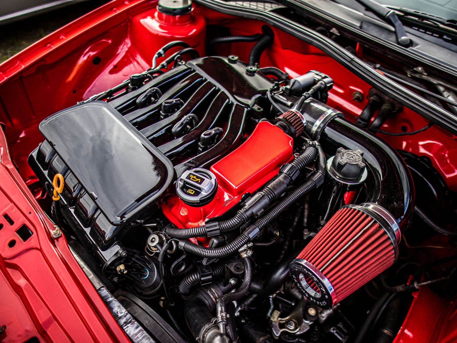 Red and black engine bay beneath an open hood