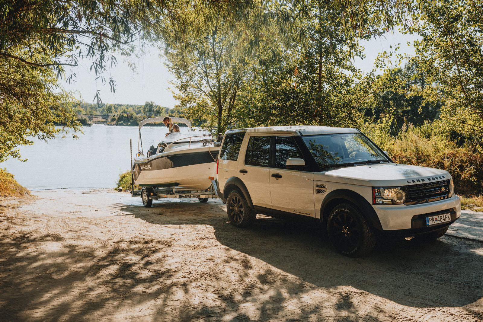 Land Rover blanco con un remolque para embarcaciones junto al agua