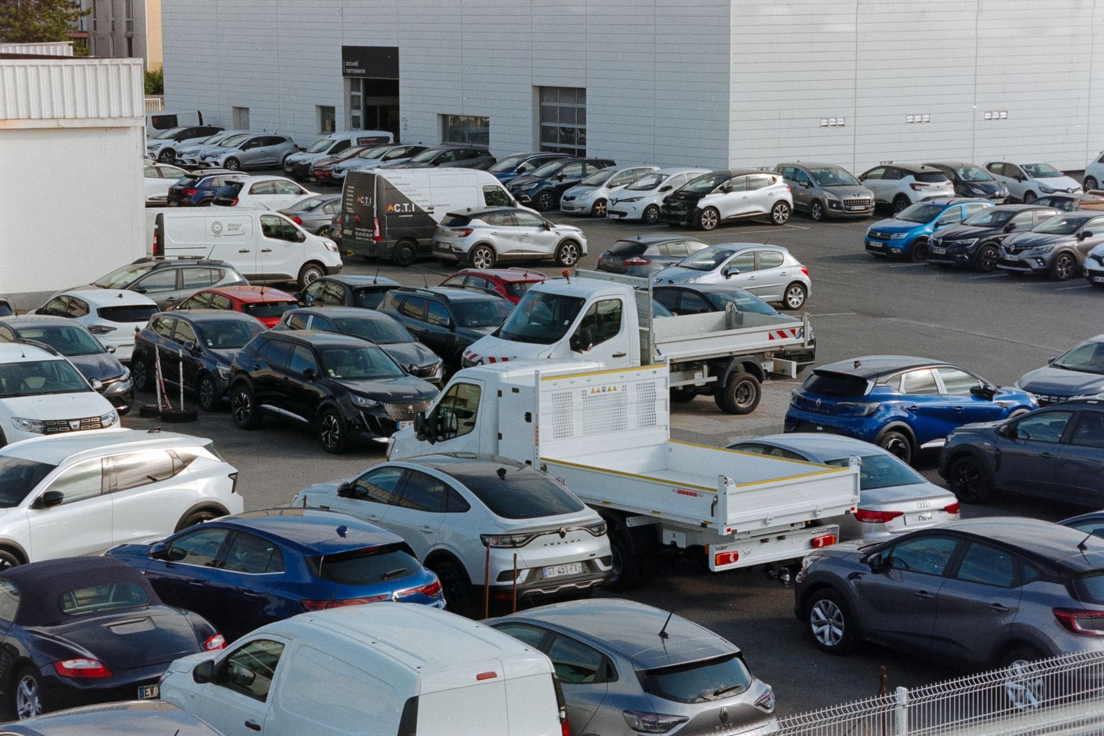 Coches, furgonetas y una camioneta plataforma aparcados en un concesionario